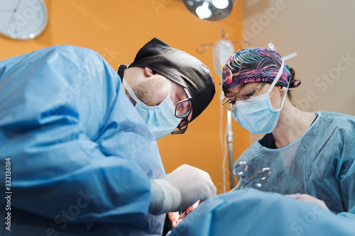Doctor with surgical tools in hands making surgery in operation room. The student observes an experienced surgeon during surgery.