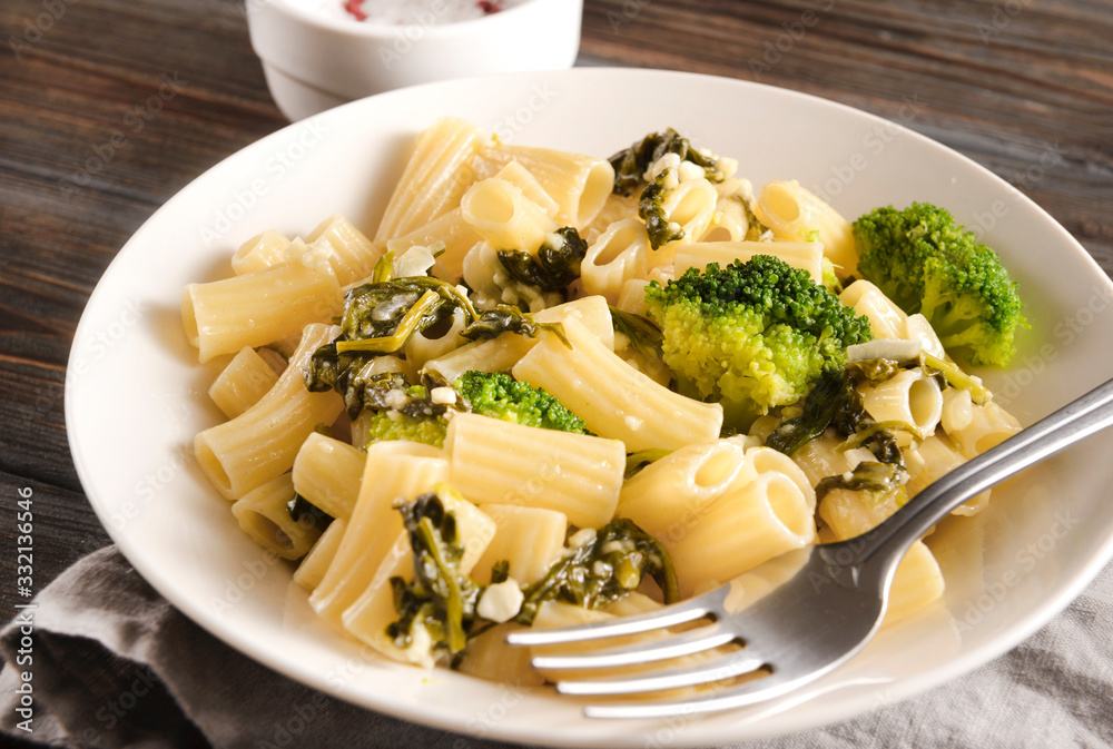 white plate with tortilloni with sauce and spinach and cheese, broccoli, fork, napkin on a light background, spinach pasta, spinach sauce pasta, top view, close -up white plate with tortilloni with sauce and spinach and cheese, broccoli, fork, napkin on a light background, spinach pasta, spinach sauce pasta, top view, close -up