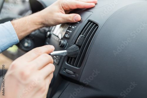 Man hands removing dust from air duct with brush.