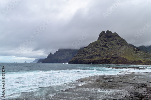 View of north of Tenerife, Punta del Hidalgo, Canary island, Spain. Mountain green landscape with ocean coast. Rainy weather and low clouds on the sharp cliffs.