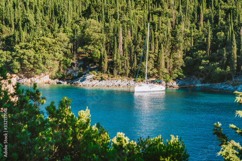 Sail boat yacht moored in the bay of Foki beach surrounded by cypress trees, Fiskardo, Cefalonia, Ionian, Greece photo