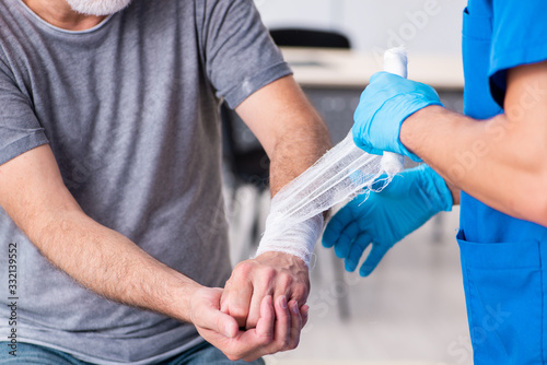 Tableau sur toile Young male doctor and old patient in first aid concept