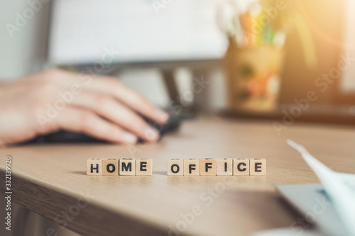 Home office concept: “Home Office” letters in foreground, man working in home office in blurry background