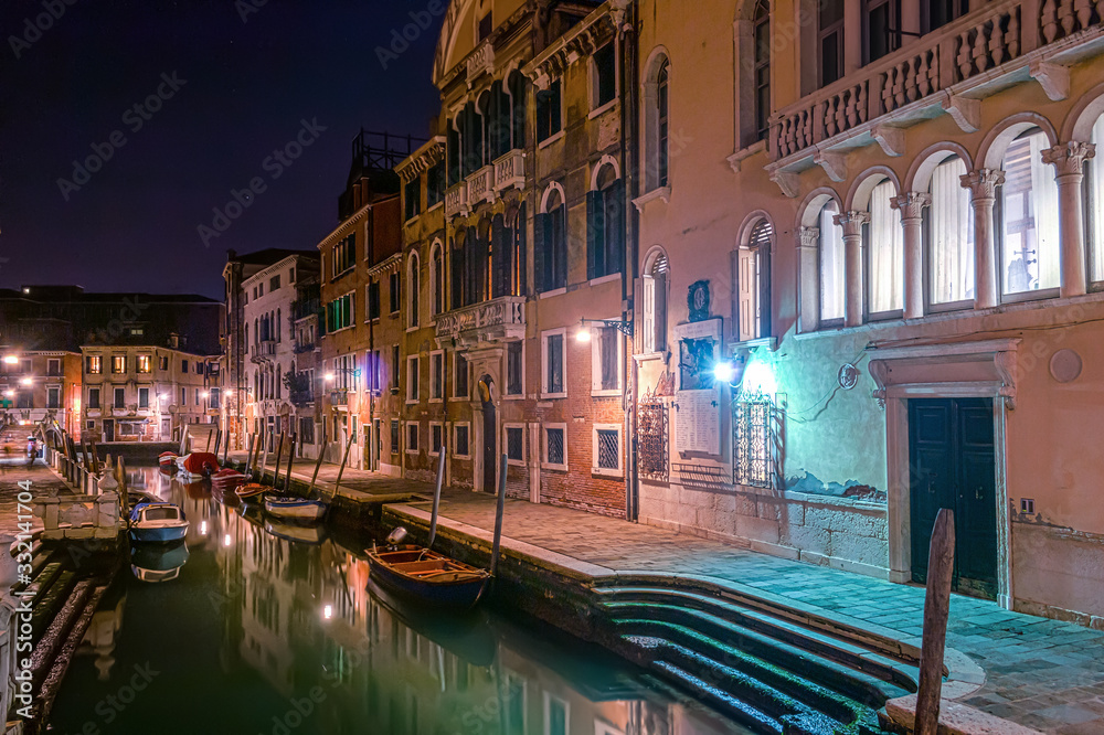 Narrow canal and historic buildings in Venice at night