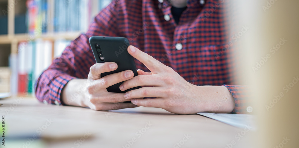 Home office concept: Man is typing on his black mobile phone Home office concept: Man is typing on his black mobile phone