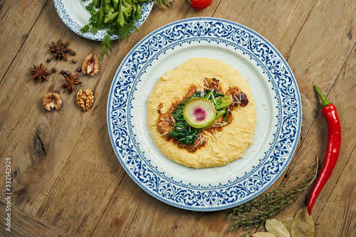 Juicy and unusual Israeli chicken steak (Pargiyot) with a side dish of polenta, corn porridge. Grilled chicken. Wooden background