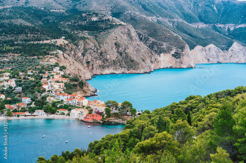 Assos cute village at Kefalonia island, Greece. Beautiful colorful town at shore with bay lagoon, pine and cypress trees, rocky coastline