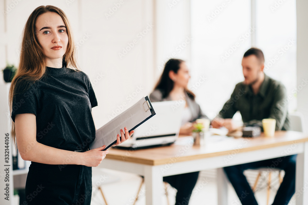 Join our team. Hiring and teamwork concept. Young successful woman standing with her co-workers at background. People, human resources and office culture Join our team. Hiring and teamwork concept. Young successful woman standing with her co-workers at background. People, human resources and office culture