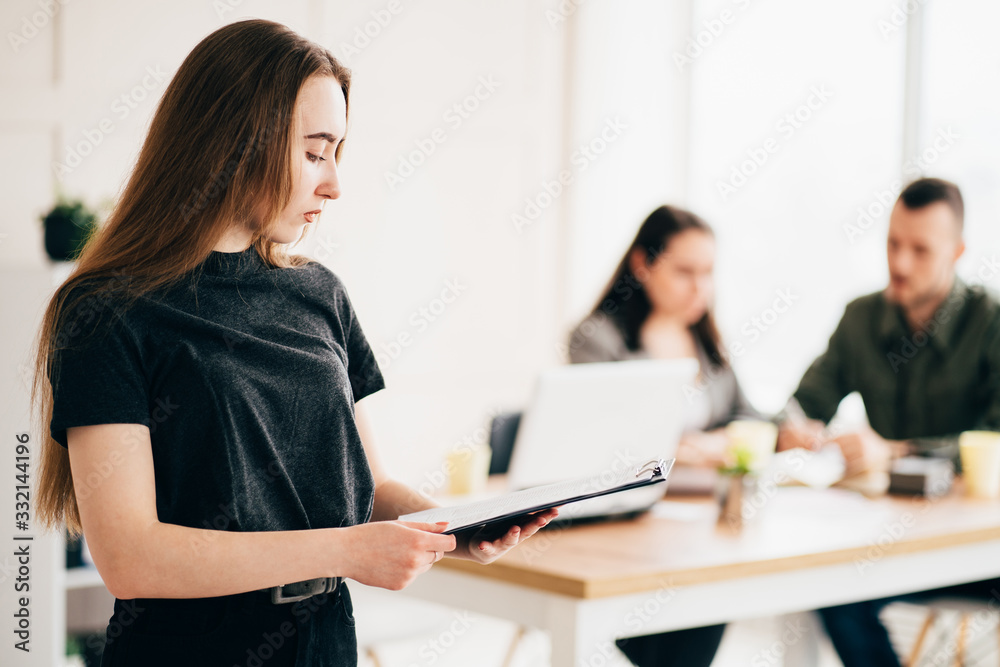 Join our team. Hiring and teamwork concept. Young successful woman standing with her co-workers at background. People, human resources and office culture Join our team. Hiring and teamwork concept. Young successful woman standing with her co-workers at background. People, human resources and office culture