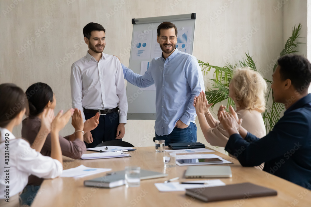 Happy young businessman introduce new male employee newcomer at office meeting, man boss congratulate worker with promotion or achievement, colleagues applaud, acknowledgment concept Happy young businessman introduce new male employee newcomer at office meeting, man boss congratulate worker with promotion or achievement, colleagues applaud, acknowledgment concept