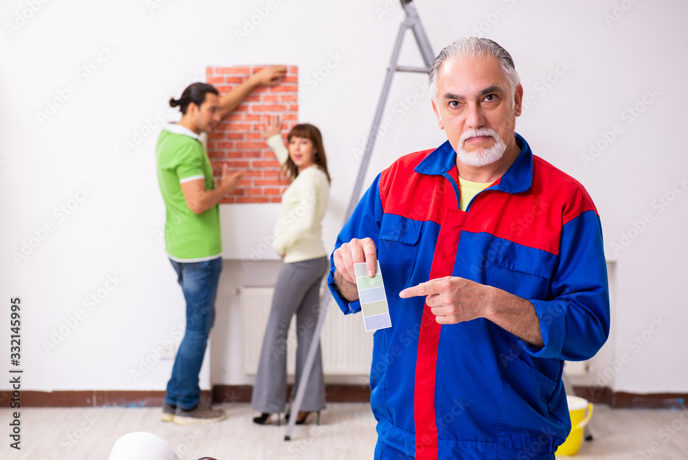 Young couple and old contractor in home renovation concept Young couple and old contractor in home renovation concept