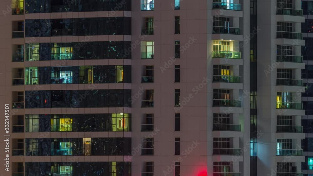 Rows of glowing windows with people in the interior of apartment building at night. Modern skyscraper from glass and concrete. Concept for business and modern life. Zoom in Rows of glowing windows with people in the interior of apartment building at night. Modern skyscraper from glass and concrete. Concept for business and modern life. Zoom in