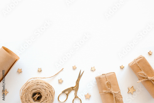 Set of materials for packing holiday gifts. Kraft paper, jute twine, scissors, boxes on white background. Holiday zero waste and eco-friendry concept. Top view Flat lay Copy space