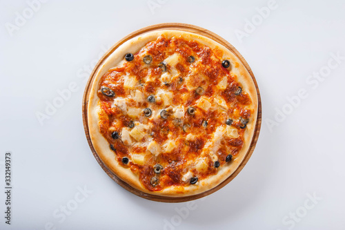 meat pizza lies on a wooden round board on a white background