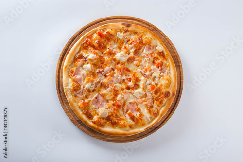 meat pizza lies on a wooden round board on a white background