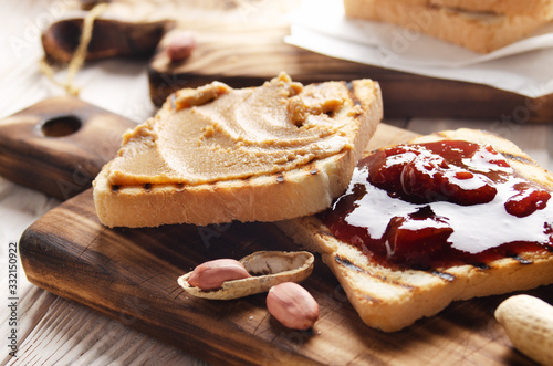 Low angle view at peanut butter and jam  sandwiches on cutting board with toasts aside. Healthy eating concept