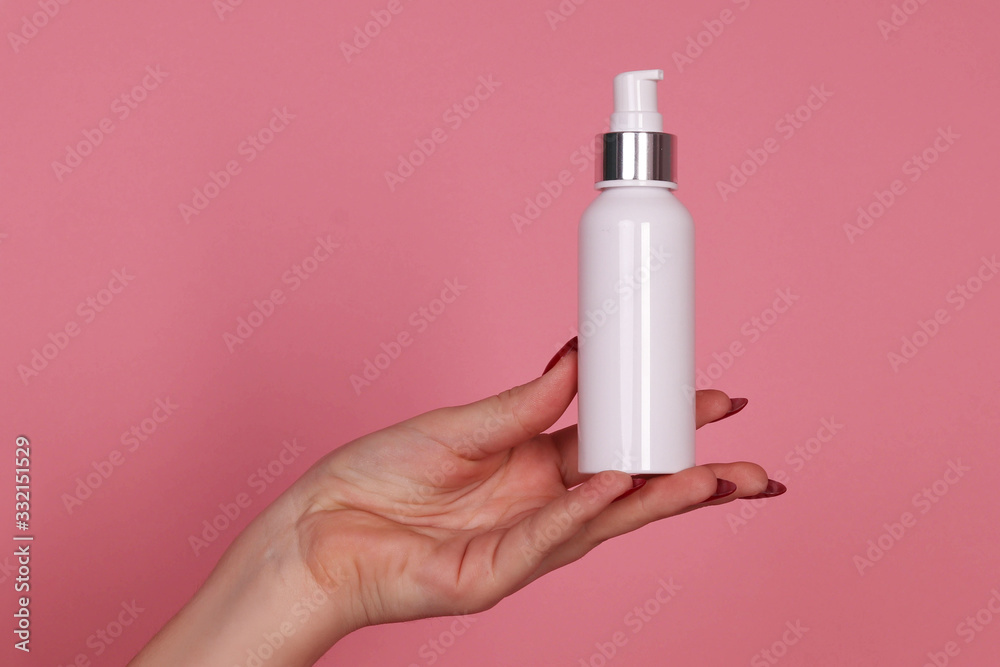 Women's hand with a jar of cream with a dispenser on a pink background Women's hand with a jar of cream with a dispenser on a pink background