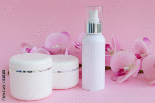 Cream in jars on a pink background and orchid flower
