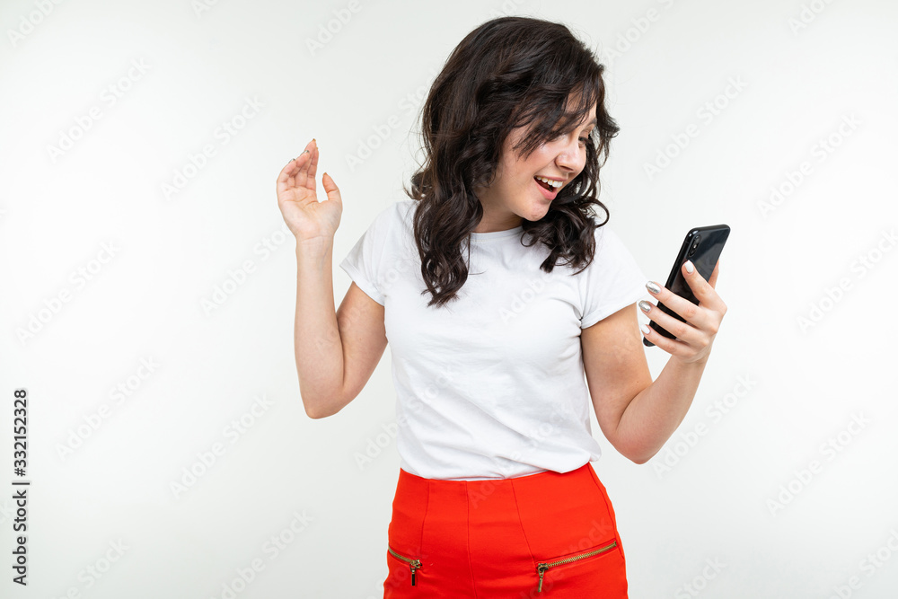cute girl talking on the speakerphone of a phone on a white studio background cute girl talking on the speakerphone of a phone on a white studio background