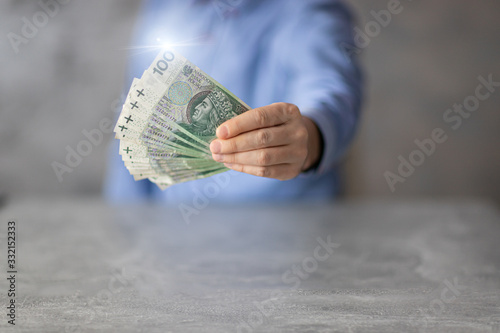 Oferta kredytowa, pożyczka. Polskie pieniądze trzymane przez bankowca w ręce.