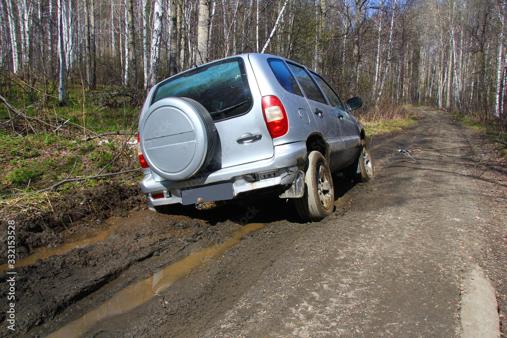 a grey SUV is towed by a hand winch out of the mud on a forest road a grey SUV is towed by a hand winch out of the mud on a forest road