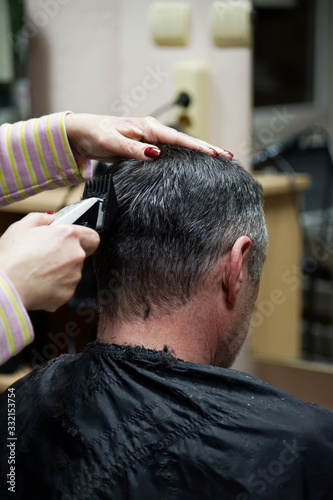 Hairdresser does haircut for middle-aged man.