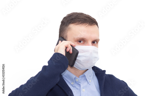 Portrait of a man on a white isolated background talking on the phone, face covered with a medical mask, banner for text. Health, awareness, and timeliness. Healthy lifestyle. No virus.