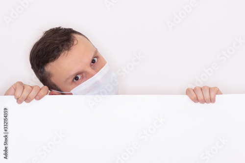 Portrait of a man on a white isolated background, face covered with a medical mask, banner for text. Health, awareness, and timeliness. Healthy lifestyle. No viruses. Fear of getting sick