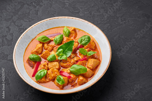 Thai Panang Chicken Curry in white plate at black slate background. Phanaeng Curry is thai cuisine dish with chicken, kaffir lime leaves, red curry sauce and vegetables. Thai food. Thailand meal