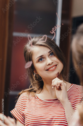 reflection of young woman face in mirror with inscription  I love you   painted heart and lip kiss  happy girl in romantic relationship  concept creative declaration of love