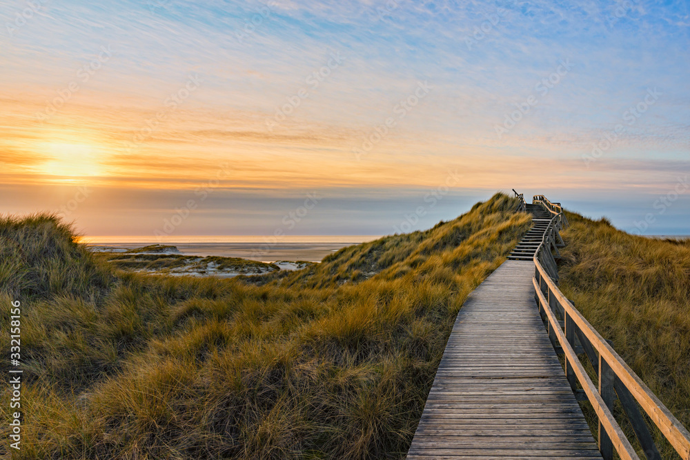 Wooden path and stairs crossing the dunes to the beach of Norddorf, Amrum, in sunset