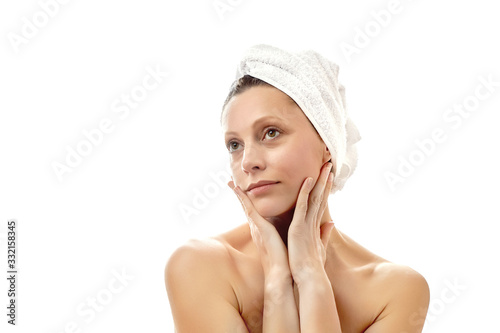 Beautiful young woman with a white towel on her head and with clean perfect skin. Facial massage at home, massage, wrinkle smoothing. Isolated white background. Isolated white background.