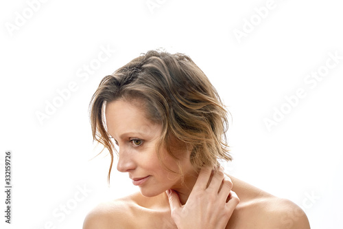 A beautiful young woman looks away and touches her face with a clean face. Naked to shoulder posing. isolated white background.