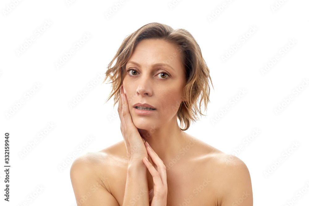 Beautiful young woman with a short haircut is touching her face skin with a slightly open mouth. Clean skin. Naked to the shoulders posing. isolated white background. Beautiful young woman with a short haircut is touching her face skin with a slightly open mouth. Clean skin. Naked to the shoulders posing. isolated white background.