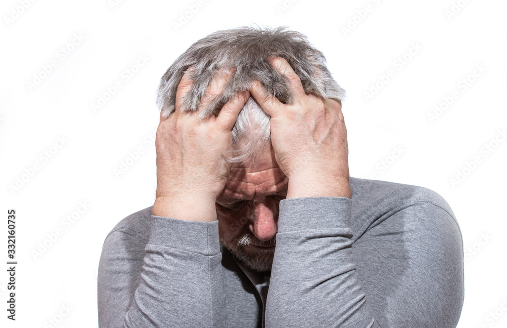 Fototapeta premium Portrait of an older man. He is holding his head with his hands in pain.