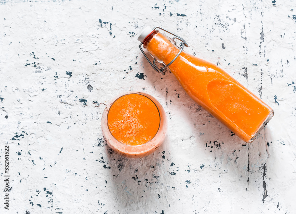 Glass and takeaway bottle with mango magic smoothies on a light background, top view.  Smoothies with ripe mango, carrot, orange, honey, ginger. Detox drink - obrazy, fototapety, plakaty 