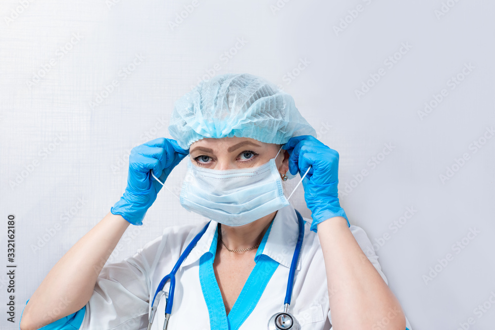 nurse in hat and rubber gloves puts on a medical mask, concept of protection against coronovirus infection nurse in hat and rubber gloves puts on a medical mask, concept of protection against coronovirus infection