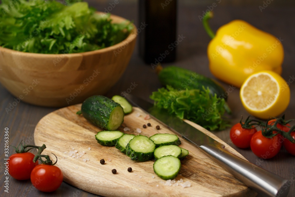 The process of preparing a fresh green salad of cucumber, cherry tomato, bell pepper, green lettuce with lemon and olive oil The process of preparing a fresh green salad of cucumber, cherry tomato, bell pepper, green lettuce with lemon and olive oil