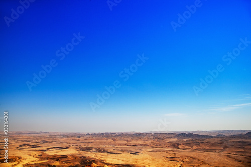 The desert during the day and above it is a huge blue sky. The scorched earth which has no punishment, a hot daylight in the desert. No animal trees and shade.