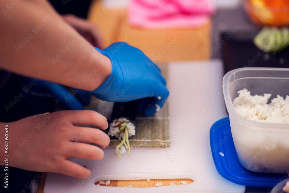 Fototapeta premium Children making sushi at the master class. Children, education and entertainment.