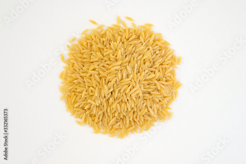 Italian pasta orzo on a white plate top view. Close-up of hard pasta in the shape of small rice. Pasta For risotto and salads.
