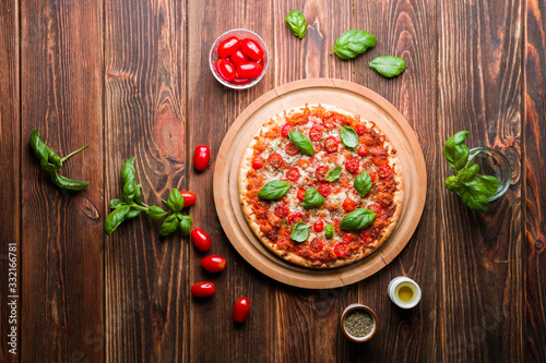 Delicious pizza with tomatoes and basil on wood.