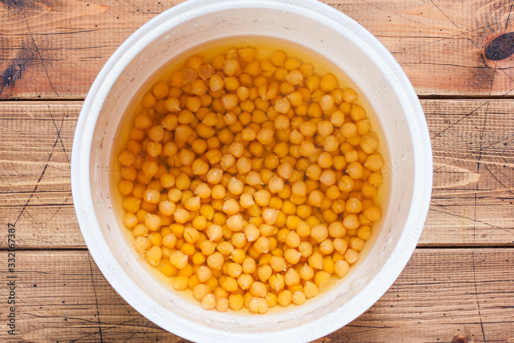 Cooked chickpeas in a pan with water on a wooden table, top view, selective focus Cooked chickpeas in a pan with water on a wooden table, top view, selective focus