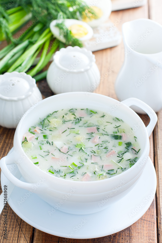 Traditional summer okroshka soup with sausage in a white bowl, selective focus