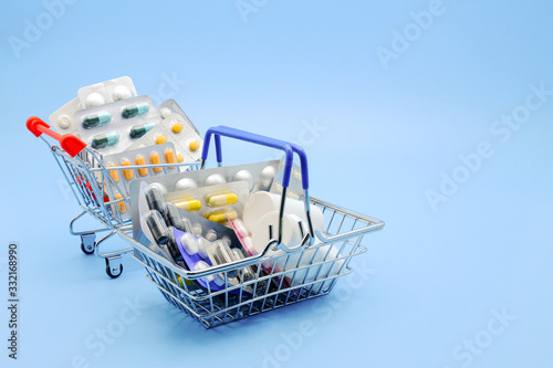 Medicine and Pill concept. Various capsules, pack of medicines in shopping basket and shopping cart with medicine bottles on a blue background. Buy and shopping medicine. Copy space.