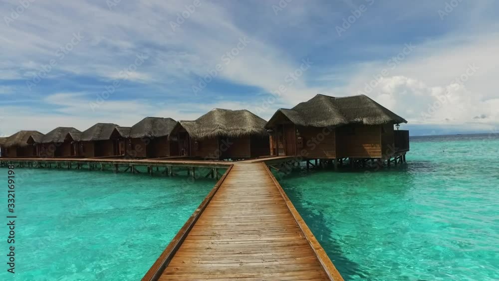 Maldive island bungalow on water. Walking on wooden bridge to luxury hotel. Maldives travel destination. Blue lagoon. Cottage in Indian ocean. Relaxation and romantic place. Resort villa in paradise. Maldive island bungalow on water. Walking on wooden bridge to luxury hotel. Maldives travel destination. Blue lagoon. Cottage in Indian ocean. Relaxation and romantic place. Resort villa in paradise.