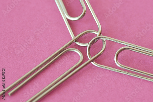Three joined paper clips on pink background - Concept of unity and solidairity between women