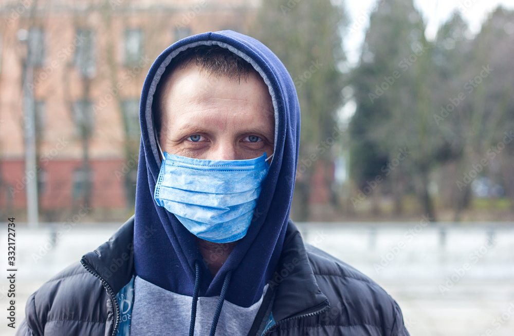 A young man in a mask to protect against coronovirus, flu and other diseases, also protection against allergies. City air pollution concept. COVID-19 Pandemic Coronavirus, Self-isolation and Quarant A young man in a mask to protect against coronovirus, flu and other diseases, also protection against allergies. City air pollution concept. COVID-19 Pandemic Coronavirus, Self-isolation and Quarant