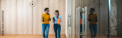 Two young coworkers meeting while they go around office hall. Group of young business people meet and discuss project on the go at coworking center
