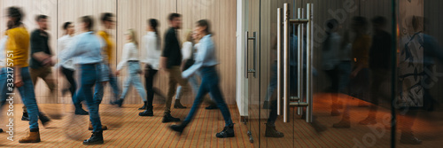 Group of business people walking at office openspace. Team of business employees at coworking center. People at motion blur. Concept working at action. Wide image